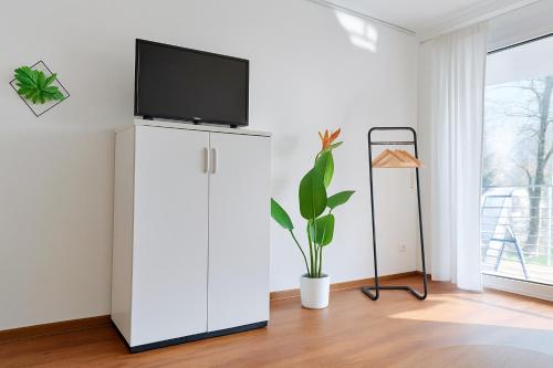 a living room with a tv on top of a white cabinet at Studioappartment mit Balkon in Langenau