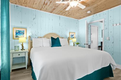 a bedroom with a white bed and a blue wall at Parrot Beach Cottages Suite #3 in Bailey Hall