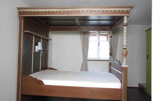 a wooden canopy bed in a room with a window at Winter'sches Haus in Nördlingen