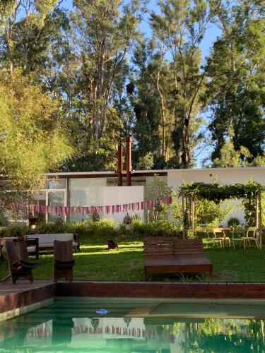 a pool with benches and chairs in a yard at Al Natural Posada in Nueva Palmira