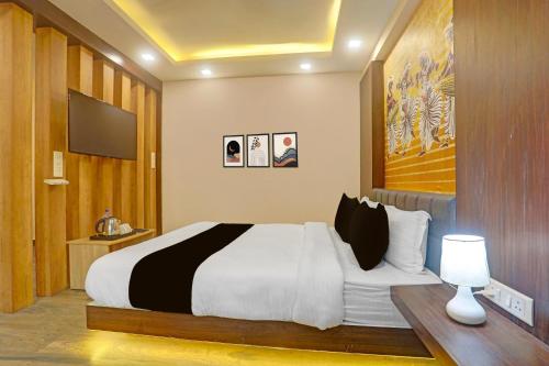 a bedroom with a large bed and a tv at Townhouse Oak City Centre Dhanbad Formerly Hotel Kuber Inn in Dhanbād