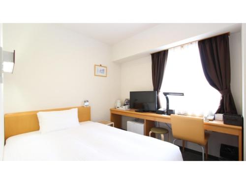 a bedroom with a bed and a desk with a computer at Smile Hotel Sakurambo Higashine - Vacation STAY 29984v in Higashine