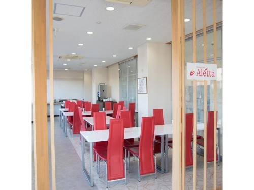 a dining room with red chairs and tables in a building at Smile Hotel Sakurambo Higashine - Vacation STAY 29990v in Higashine