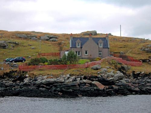 a house on top of a hill next to the water at 3 Bed in Isle of Barra CA295 in Ersary