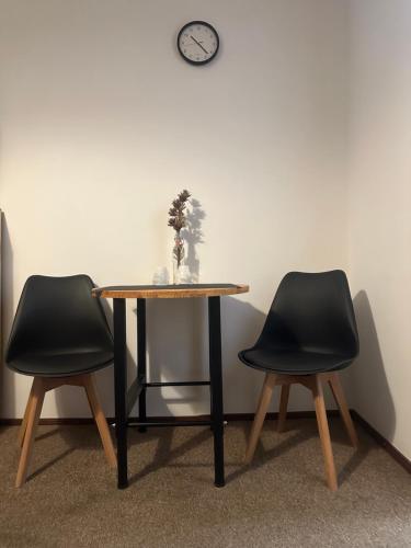 a table with two chairs and a clock on a wall at Hotel Olimpijski in Tarnowskie Góry