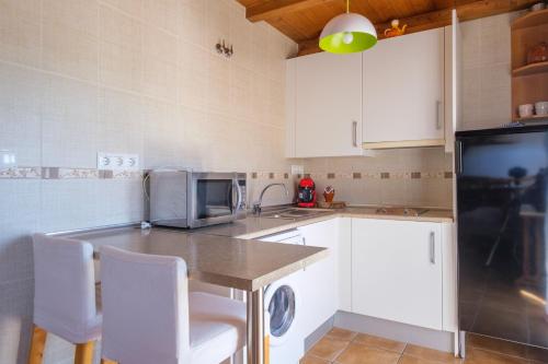 a kitchen with white cabinets and a table with chairs at Casa Maza Apartamentos in Biescas