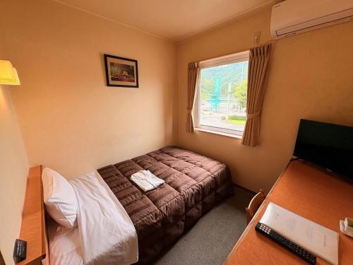 a small bedroom with a bed and a window at Maniwa City Hotel Sunrise - Vacation STAY 98578v in Maniwa