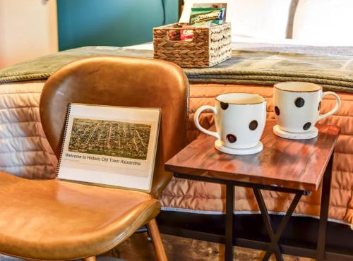 two coffee cups and a table with a book at Historic OLD TOWN Block 2 KING ST 99 Walkscore in Alexandria