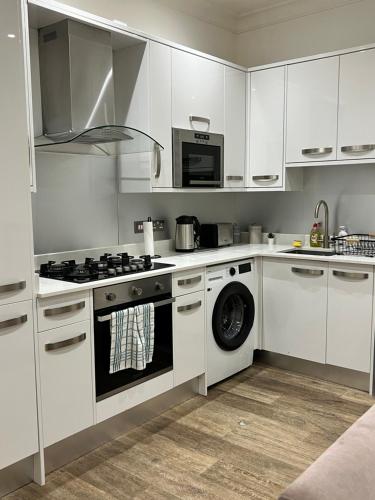 伦敦2 bed flat, sleeps 8, driveway, 5 Mins to Brixton的白色的厨房配有炉灶和洗碗机。