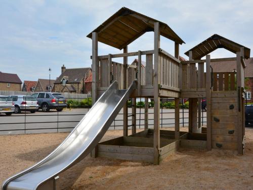 a wooden playground with a slide in a parking lot at 2 Bed in Filey 89281 in Hunmanby
