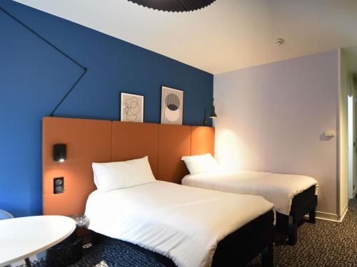 a room with two beds and a blue wall at ibis Laval Le Relais D'Armor in Laval