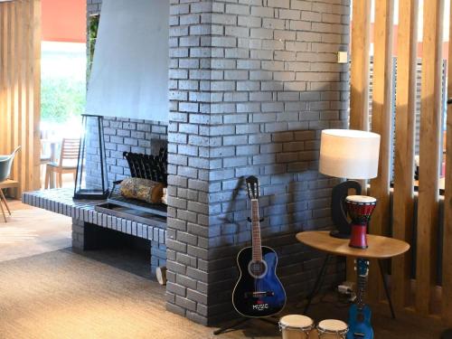 a brick fireplace with a guitar next to a lamp at ibis Laval Le Relais D'Armor in Laval