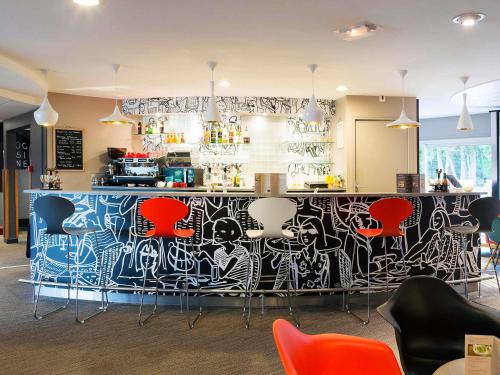 a restaurant with a bar with graffiti on the wall at ibis Laval Le Relais D'Armor in Laval