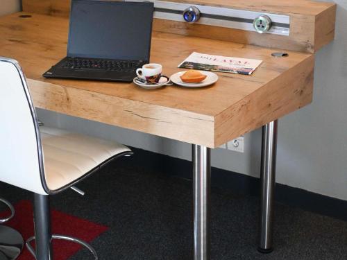 a desk with a laptop and a cup of coffee on it at ibis Laval Le Relais D'Armor in Laval
