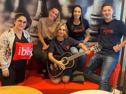 a group of people posing for a picture with a guitar at ibis Lorient Centre Hôtelier in Caudan