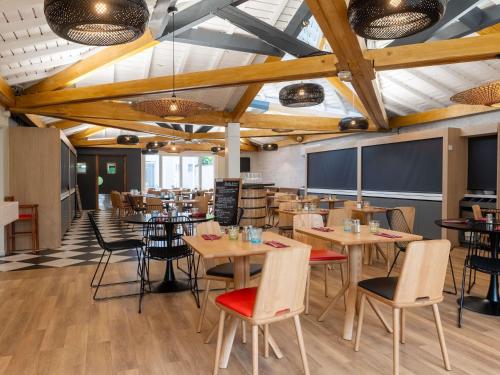 a dining room with wooden tables and chairs at ibis Lyon Est Bron in Bron