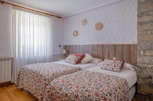 a hotel room with two beds and a window at Casa Maza Apartamentos in Biescas