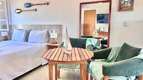 a bedroom with a bed and two chairs and a table at Bella Buzios Apartamentos in Búzios