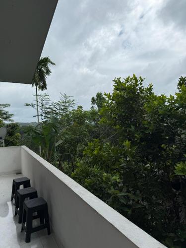 two stools on a balcony with a view of trees at Kandy Home stay in Katugastota