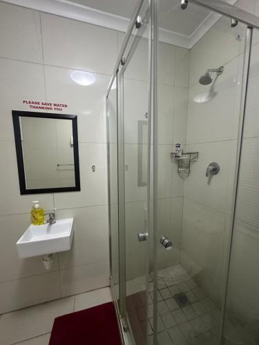a bathroom with a glass shower and a sink at Surrey B&B in Surrey Estate
