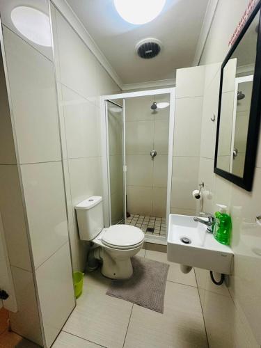 a white bathroom with a toilet and a sink at Surrey B&B in Surrey Estate