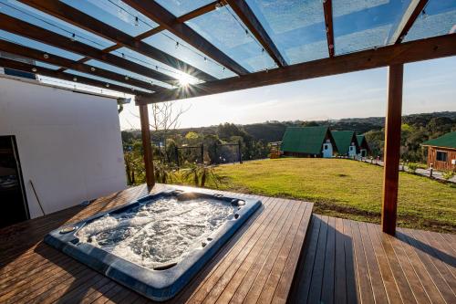 a hot tub on a deck with a view of a yard at Chácara Cabanas e Eventos Peniel in Campina Grande do Sul