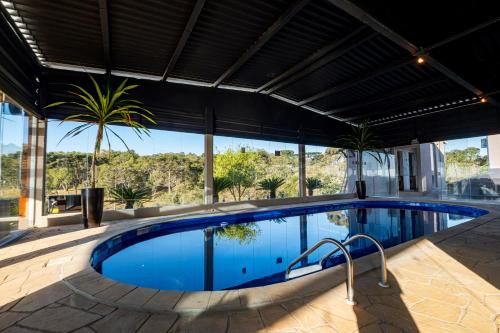 a swimming pool with a view of a house at Chácara Cabanas e Eventos Peniel in Campina Grande do Sul