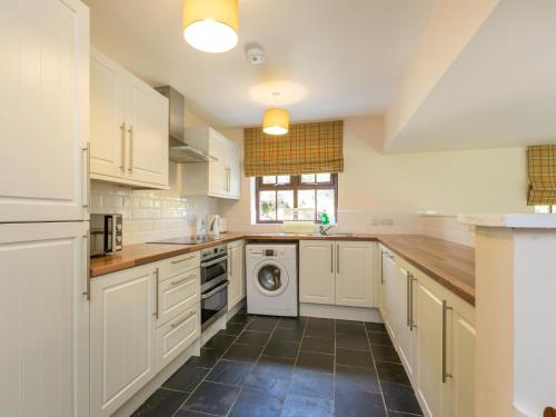 a kitchen with white cabinets and a washer and dryer at 1 Bed in Cairnbaan CA304 in Lochgilphead