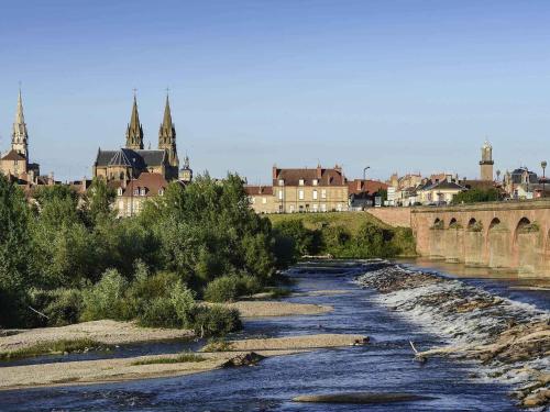 a river in a city with a bridge and buildings at ibis Moulins in Moulins