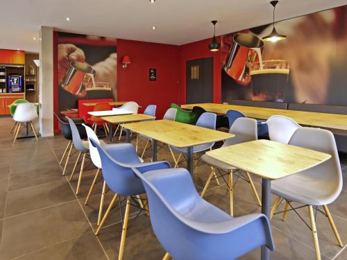 a restaurant with wooden tables and blue chairs at ibis Moulins in Moulins