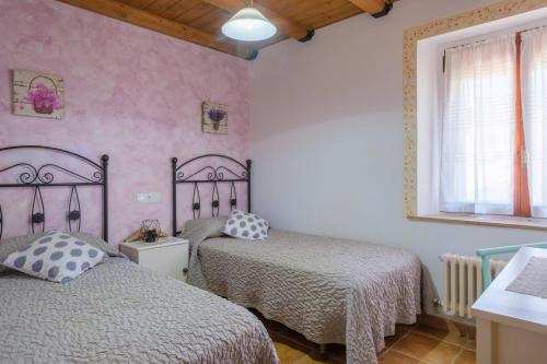 two beds in a bedroom with pink walls at Casa Maza Apartamentos in Biescas