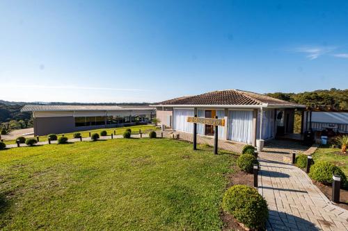 a house with a sign in front of a yard at Chácara Cabanas e Eventos Peniel in Campina Grande do Sul