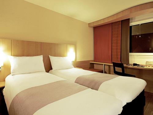 a hotel room with two beds and a desk at ibis Paris Porte d'Italie in Paris