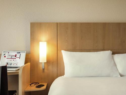 a bedroom with a bed and a desk with a laptop at ibis Paris Porte D'Orleans in Montrouge