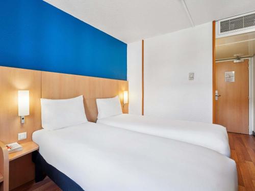 a large white bed in a room with a blue wall at ibis Paris Porte D'Orleans in Montrouge