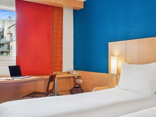 a bedroom with a bed and a desk with a laptop at ibis Paris Porte D'Orleans in Montrouge