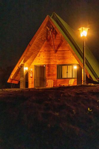 a log cabin with a street light at night at Chácara Cabanas e Eventos Peniel in Campina Grande do Sul