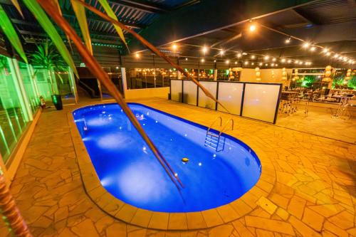 a large blue swimming pool in a room with lights at Chácara Cabanas e Eventos Peniel in Campina Grande do Sul
