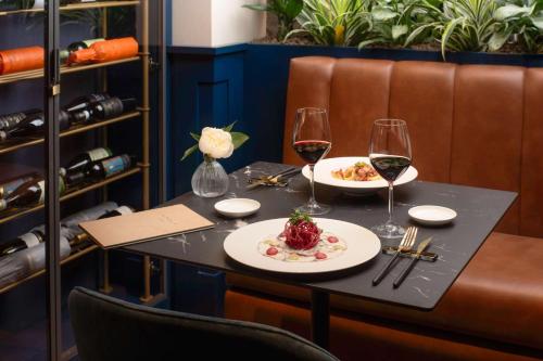 a table with two glasses of wine and food at NH Collection Roma Centro in Rome