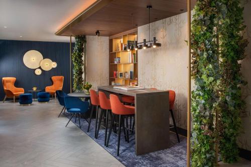 a lobby with a bar with chairs and plants at NH Collection Roma Centro in Rome