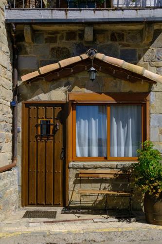 a building with a wooden door and a window at Casa Maza Apartamentos in Biescas