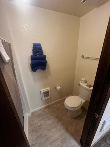 a bathroom with a toilet and a stack of blue towels at Dove Creek Inn in Dove Creek