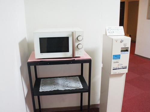 a microwave sitting on a stand next to a refrigerator at Hotel Abest Osu Kannon Ekimae Hane no Yu in Nagoya