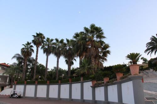 a white fence with palm trees in the background at Villa Caribe Resort & Spa in Spigno Saturnia