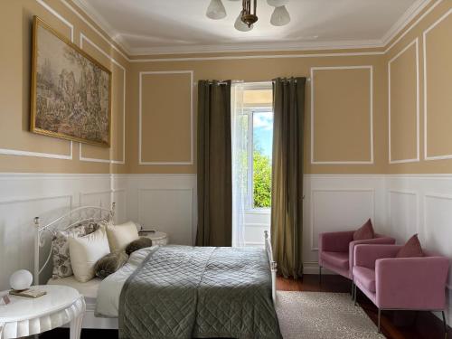 a bedroom with a bed and two chairs and a window at Villa Várzea - Garden Suite in Várzea