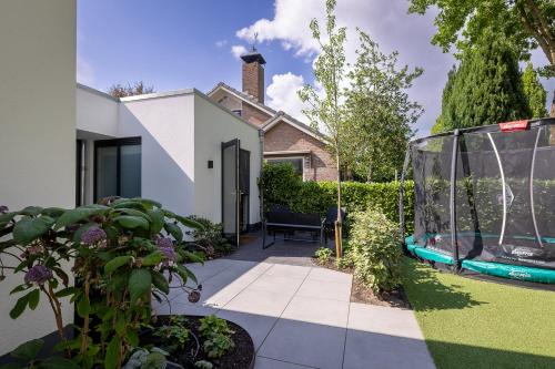 a garden with a swing and a house at De Aanbouw van Foonloos - luxe studio vlakbij Utrecht in Houten