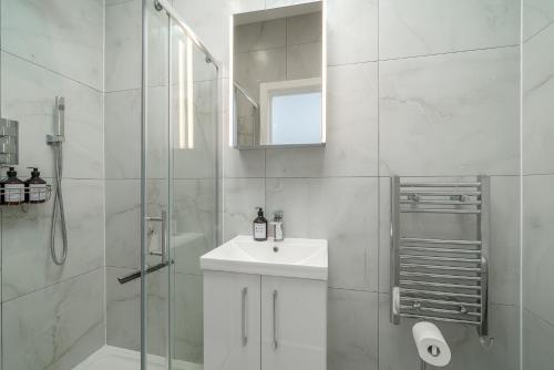 a white bathroom with a sink and a shower at Stylish apartment in the heart of Kingston Town Centre in Kingston upon Thames