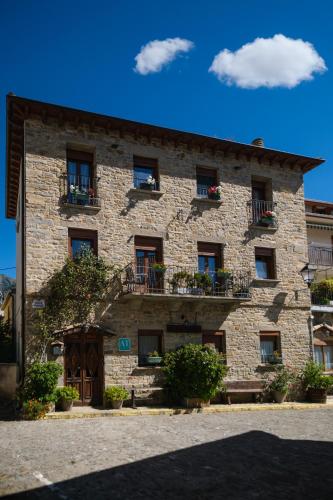 a large stone building with windows and flower boxes at Casa Maza Apartamentos in Biescas