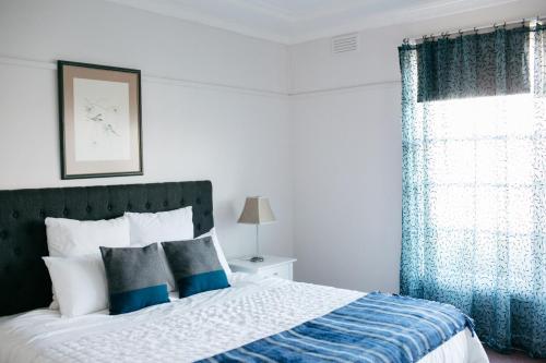 a bedroom with a bed with blue curtains and a window at Goldies on Piper Kyneton in Kyneton