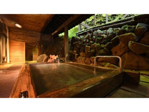 a hot tub in a building with a bunch of rocks at Osakaya Ryokan - Vacation STAY 30202v in Kusatsu